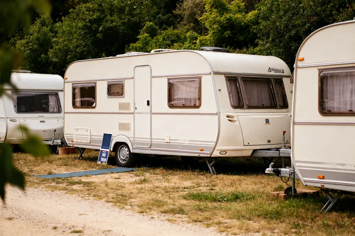 Caravanes blanches stationnées sur herbe avec panneau, liées à l'Argus des caravanes.