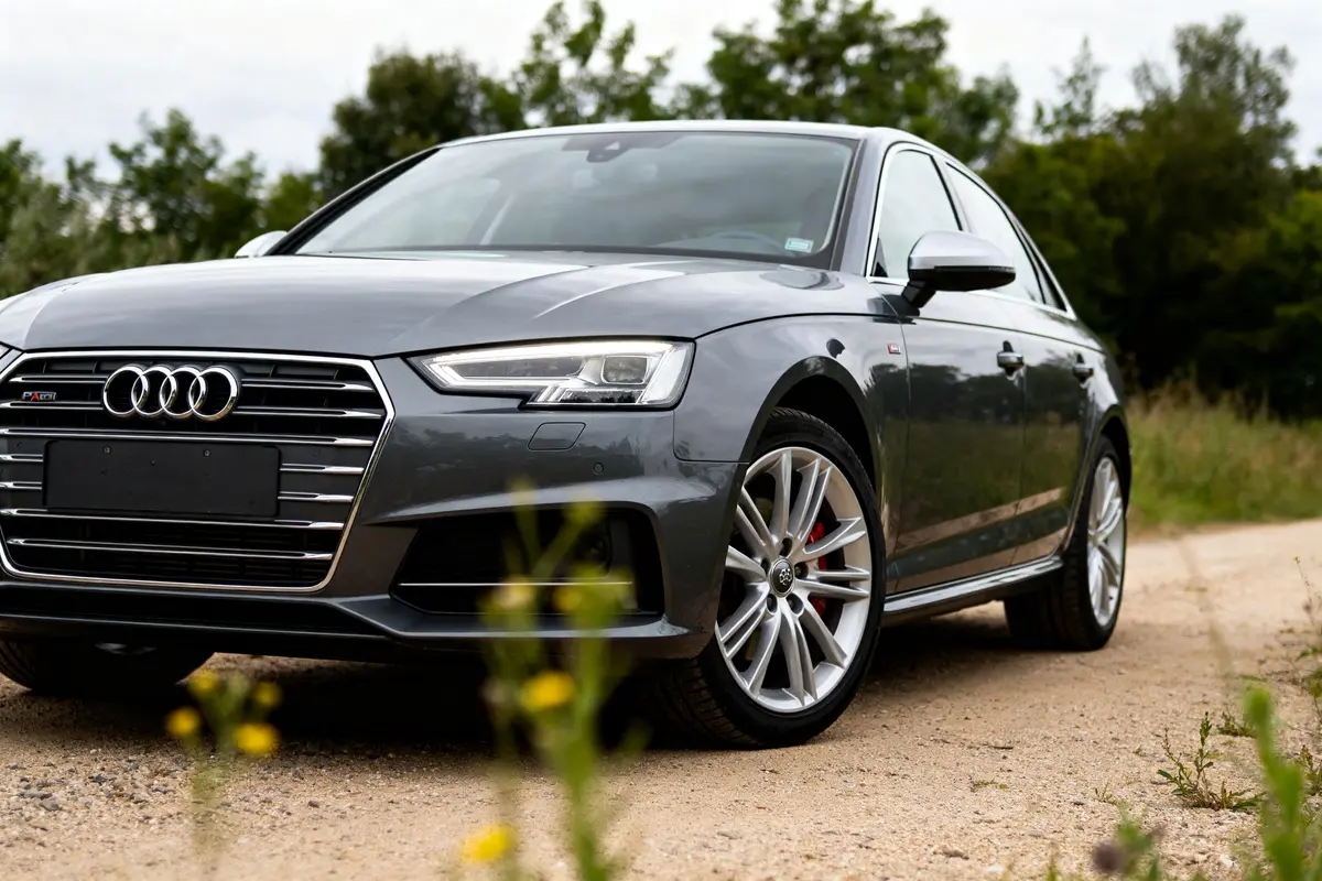 Berline Audi A4 grise garée sur un chemin rural avec végétation en arrière-plan