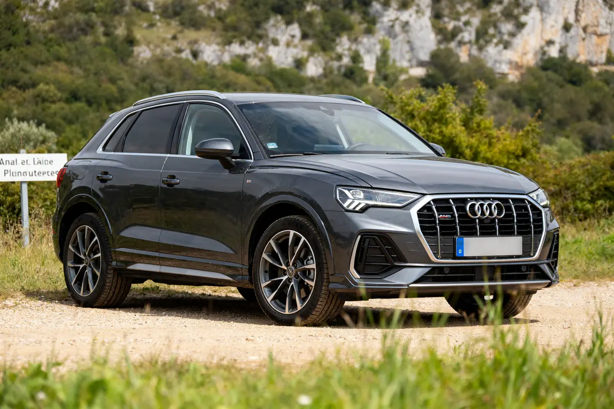 SUV Audi Q3 gris stationné sur un chemin de terre en pleine nature.