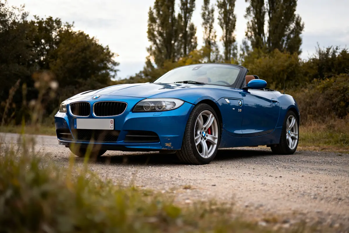 Voiture décapotable bleue garée, modèle BMW Z4 Coupé 3.0 si, sur chemin gravillonné