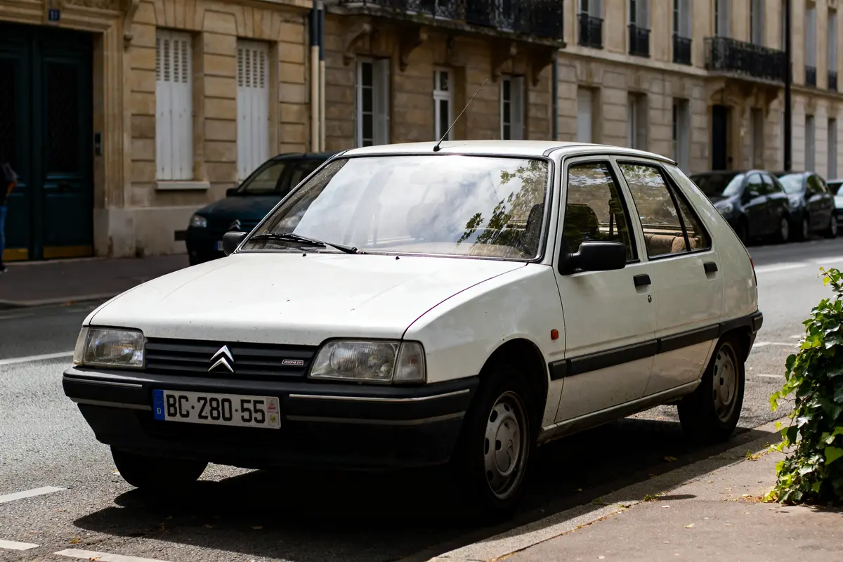 Voiture Citroën Visa blanche garée sur une rue bordée d'immeubles anciens