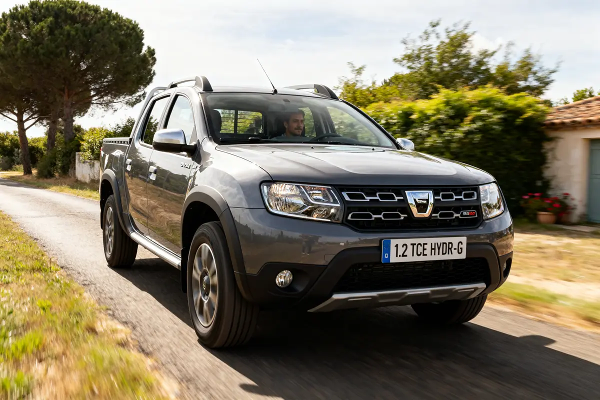 Dacia Duster Pick-up gris roulant sur une route de campagne avec conducteur visible