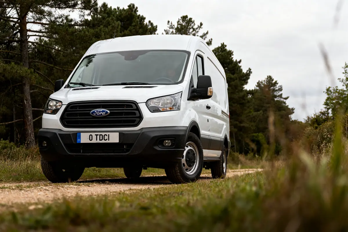 Fourgon blanc Ford Transit 2.0 TDCi sur chemin forestier avec fond boisé verdoyant