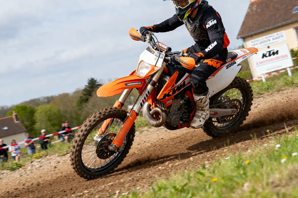 Motard effectuant un virage serré sur KTM 125 SX lors d'une course en plein air
