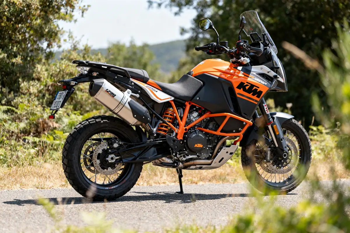 Moto aventure KTM 1290 Super Adventure R orange sur route entourée de verdure