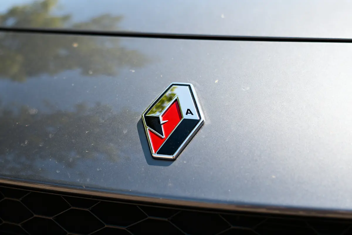 Logo de Renault Alpine sur le capot d'une voiture, fond gris sombre