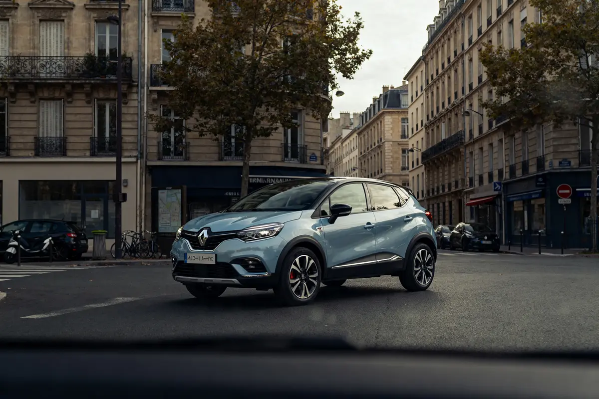 Renault Captur Mild Hybrid 140 bleu circulant dans une rue urbaine bordée d'immeubles anciens