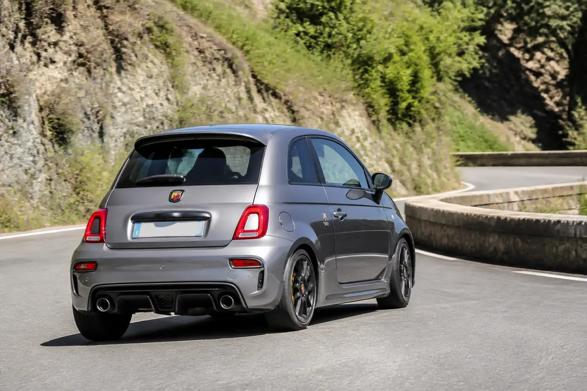 Petite berline sportive Abarth 595 Competizione grise sur route sinueuse en montagne