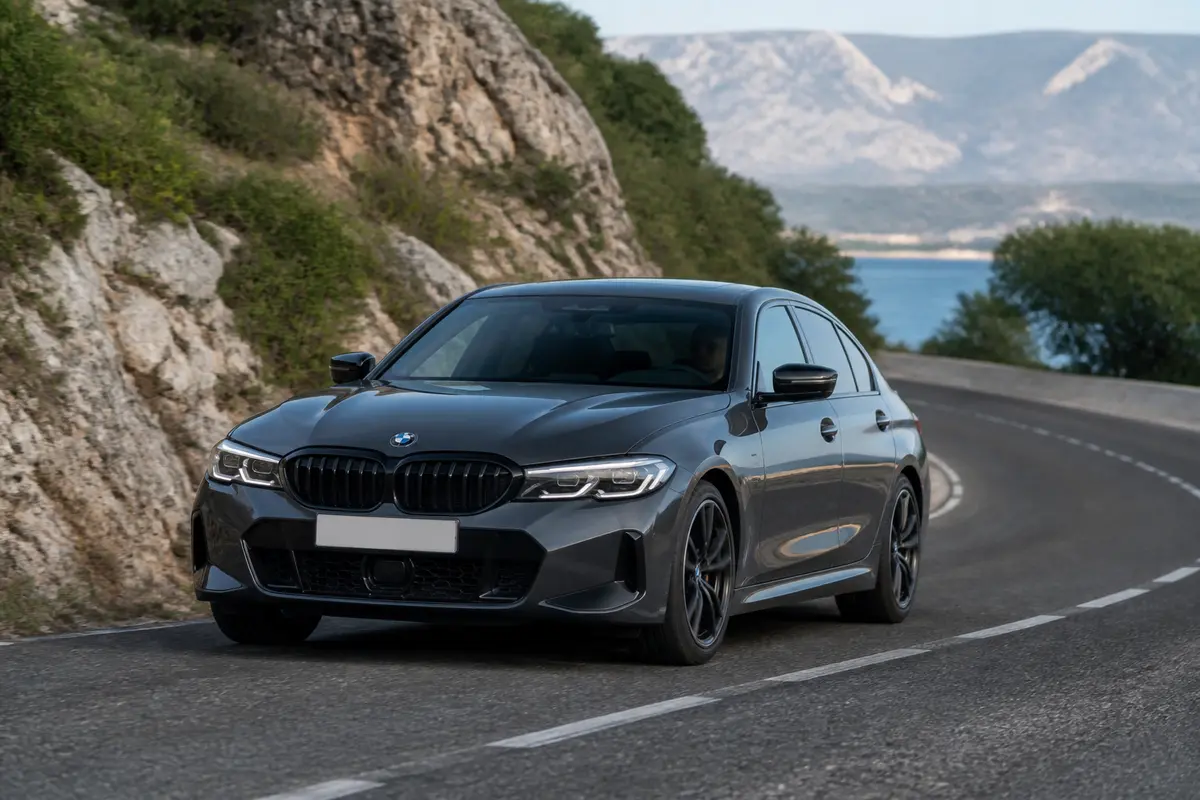 BMW Série 3 sur route côtière avec paysage montagneux en arrière-plan