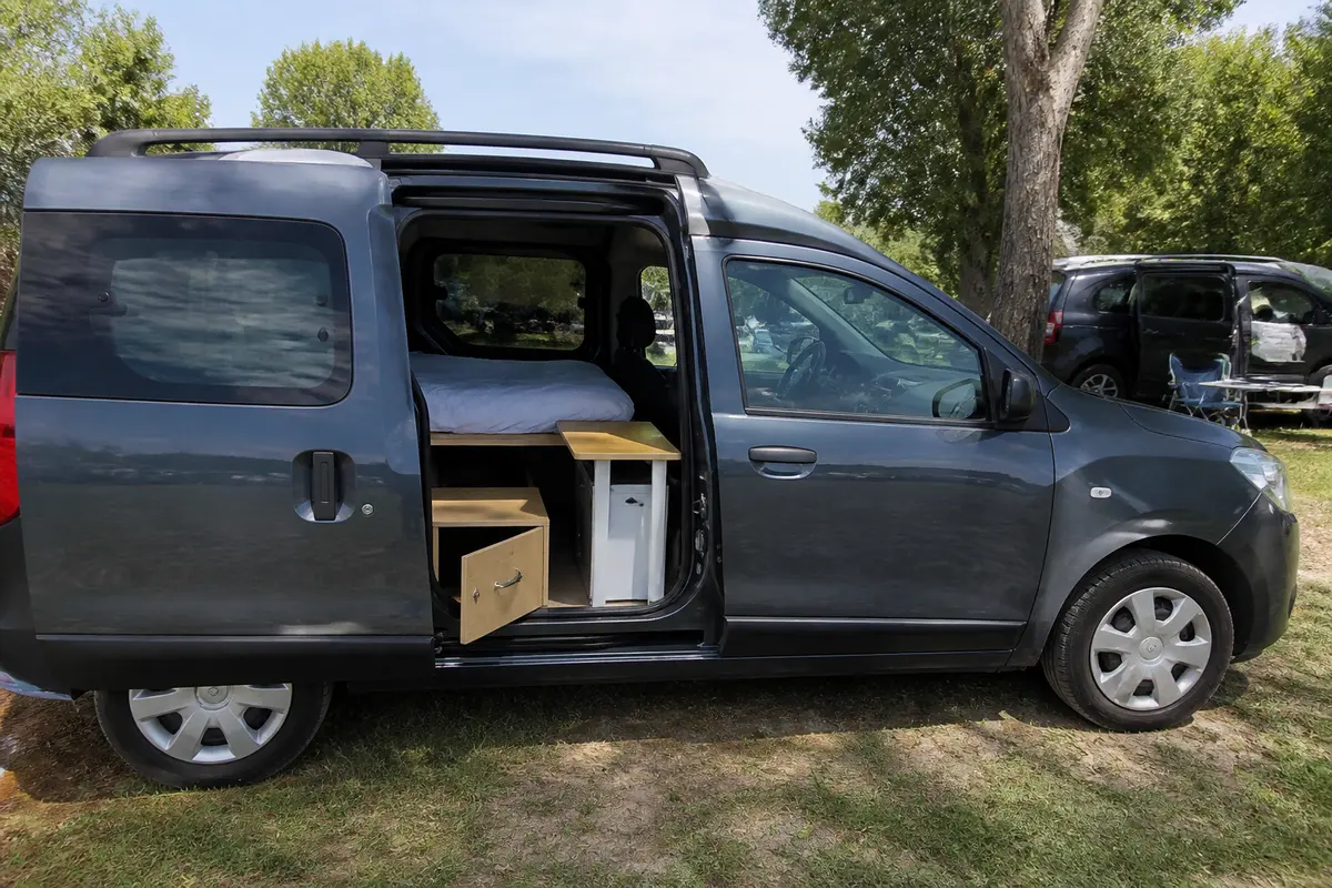 Van Dacia Dokker aménagé avec lit et rangements en camping.