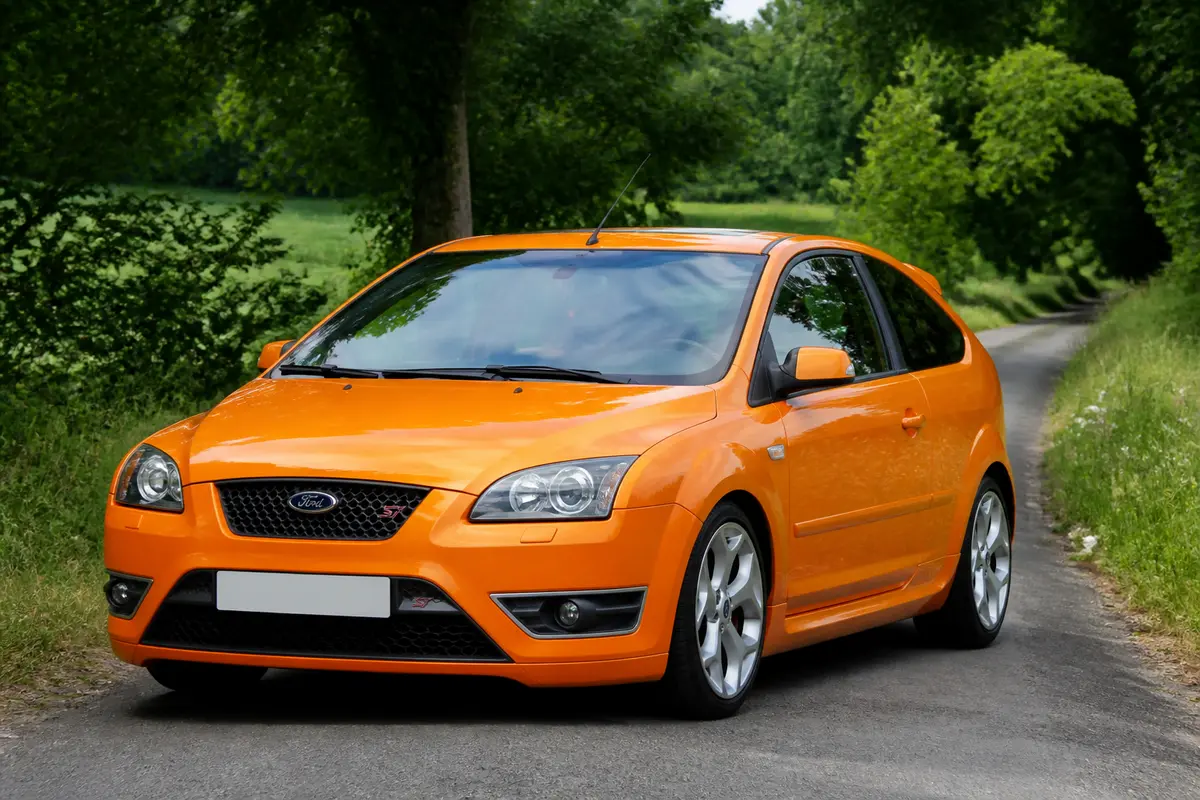 Voiture orange Ford Focus ST 2 garée sur une route entourée de verdure