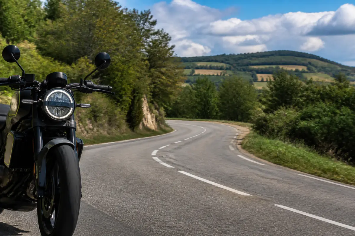 Moto Husqvarna Vitpilen 701 sur route sinueuse bordée d'arbres en campagne