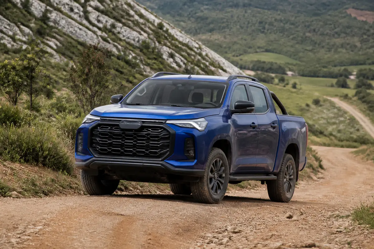 Pickup bleu Maxus T60 sur chemin de terre en paysage montagneux verdoyant
