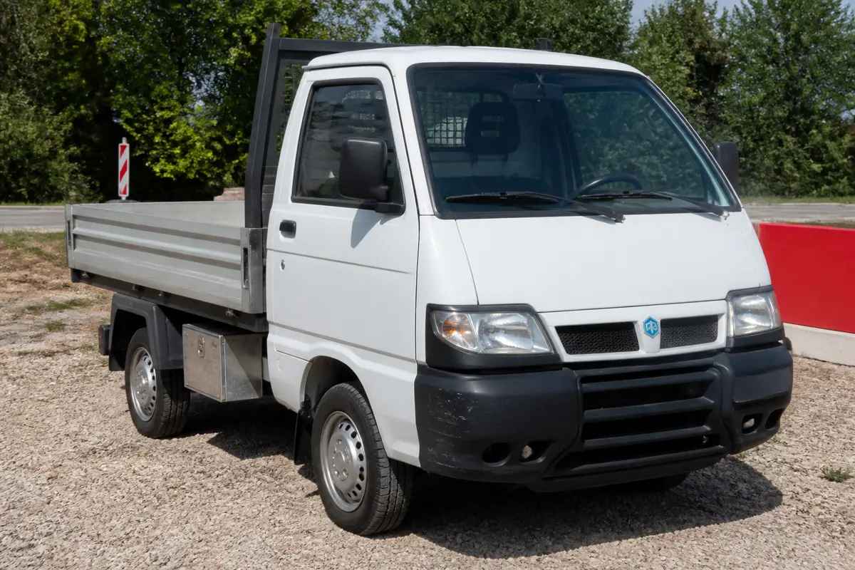 Utilitaire blanc stationné en extérieur, modèle Piaggio Porter d'occasion disponible à vendre
