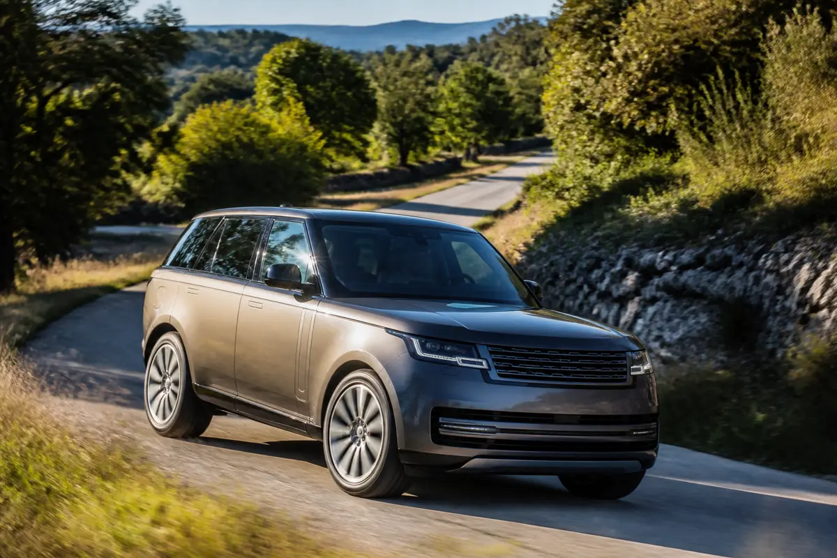 Range Rover sur route de campagne entourée de végétation luxuriante et collines lointaines