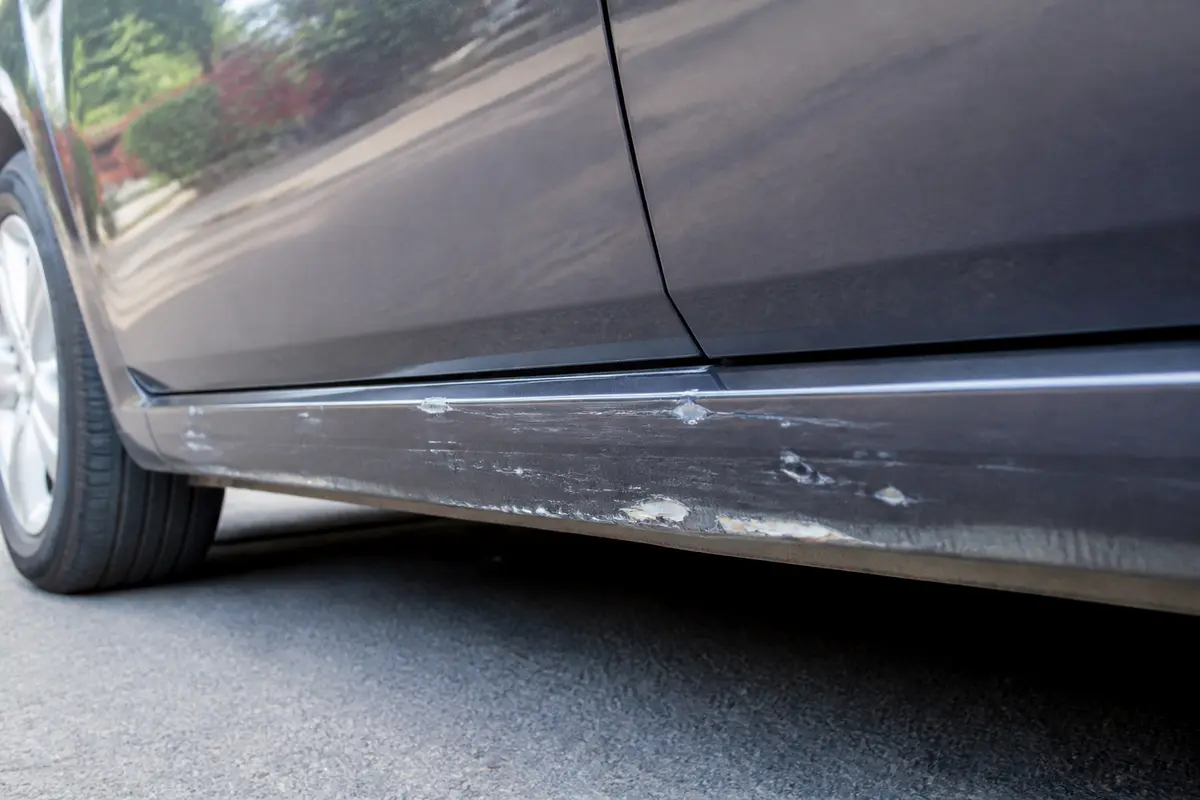 Bas de caisse de voiture avec rayures et éraflures visibles sur la peinture