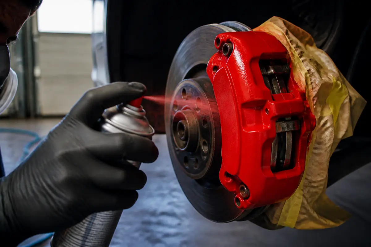 Application de peinture pour étrier de frein avec aérosol rouge sur voiture